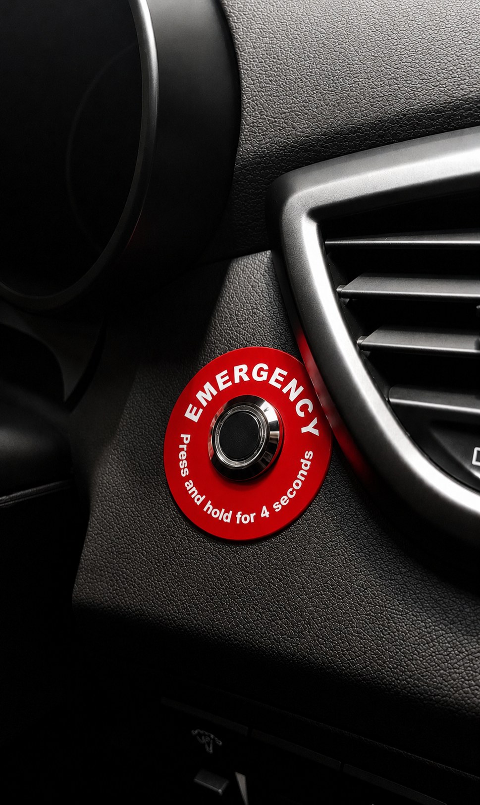Sensium in-vehicle panic button — red EMERGENCY disc with 'Press and hold for 4 seconds' label, mounted on a vehicle dashboard.
